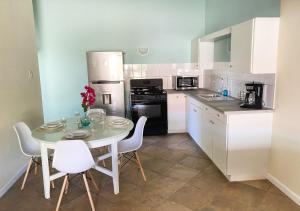 努尔德Pura Vida Aruba Appartement Palma的一间带桌椅的厨房和一间带白色橱柜的厨房