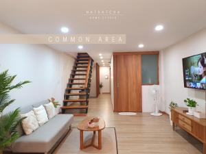 清迈NatRatcha Home Studio的带沙发和螺旋楼梯的客厅