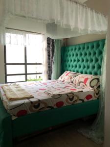 VipingoVipingo Palm - 3BDR Apartment的一间卧室配有一张带绿色床头板的床和窗户