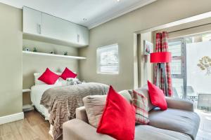 开普敦Fairmile on Main的一间卧室配有一张带红色枕头的床和一张沙发
