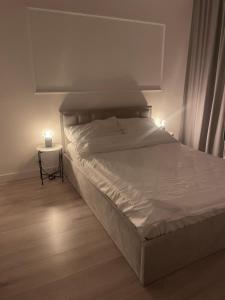 华沙AirPort Apartment的卧室内的一张床铺,边桌上放着两根蜡烛