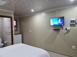 理查兹湾Airport Airbnb的卧室配有一张床,墙上配有电视。