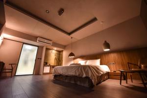 台南贰侣休闲艺术旅馆的一间卧室配有一张床、一张桌子和一个窗户。