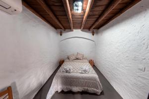 Casa Rural El Palomeque的一间小卧室,卧室的白色墙壁上配有一张床
