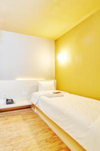 台北单人房住宿空间 - 台北馆的卧室配有白色的床和黄色的墙壁