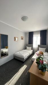 华沙Lezzet Hotel & Turkish Restaurant的一间设有两张床和一张鲜花桌的房间