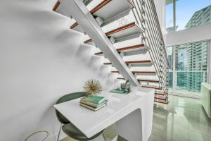 迈阿密Modern 2 Story Loft 2BR with Breathtaking Views的客厅的楼梯,配有白色的桌子和椅子
