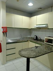 迪拜Rovers Boys Hostel Dubai Near Gold Souq Metro的厨房配有白色橱柜和花岗岩台面