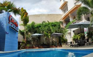 El PedregalCucaña Hotel的酒店前方的游泳池配有桌子和遮阳伞