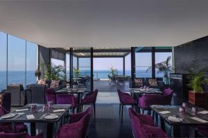 科伦坡Radisson Hotel Colombo的一间设有紫色桌椅的餐厅,享有海景