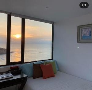 曼塔Departamento vista al mar en Manta Poseidon的客房设有沙发和带大窗户的书桌。