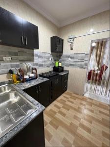 拉各斯Melford Homes的厨房配有黑色橱柜和木地板