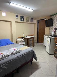 内乌肯Departamentos Confluencia的一间卧室配有一张床,厨房配有桌子