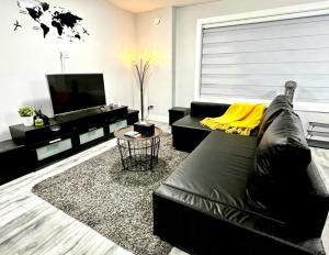 三角洲Luxurious & Stylish Two Bedroom Suite, Full Kitchen, Close to Vancouver的客厅配有黑色真皮沙发和电视