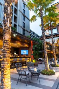 华欣Maven Stylish Hotel Hua Hin的一个带桌椅的庭院,棕榈树