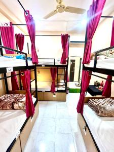 乌贾因The BackpackStack的带3张双层床和粉红色窗帘的房间