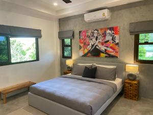 苏梅岛PATAMAAN COTTAGES的卧室配有一张床,墙上挂有绘画作品