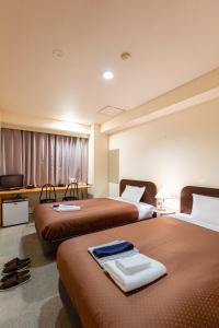 米子市米子シティガーデンズホテル Yonago Citygardens Hotel的酒店客房设有两张床和电视。