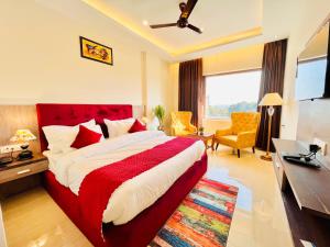 瑞诗凯诗Ganges Blossam, Haridwar-Rishikesh Road - A Four Star Luxury Hotel的一间卧室配有一张床、一张书桌和一台电视