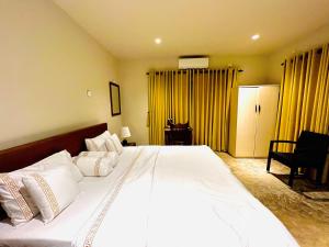 尼甘布Ceylon Kingsmen Garden Hotel - Katunayake的卧室配有一张白色大床和黄色窗帘