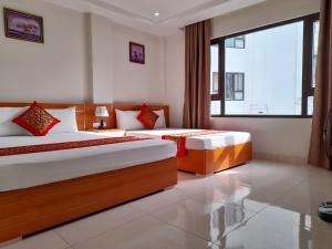 下龙湾Sail Hotel Hạ Long的一间卧室设有两张床和大窗户