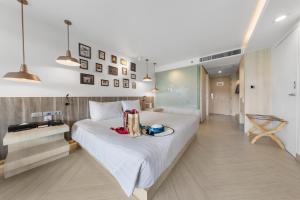 北芭堤雅芭堤雅金色郁金香海滩度假酒店的卧室配有一张白色大床,上面有盘子