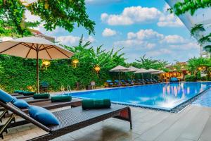 会安Wyndham Garden Hoi An Cua Dai Beach的度假村的游泳池,配有椅子和遮阳伞