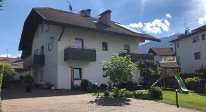 布鲁尼科Apartment Obermair的前面有游乐场的白色房子