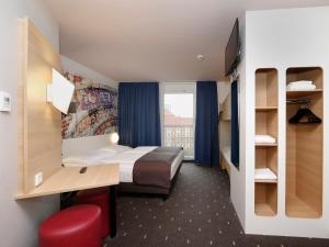 柏林B&B HOTEL Berlin-Alexanderplatz的配有一张床、一张书桌和一扇窗户的酒店客房