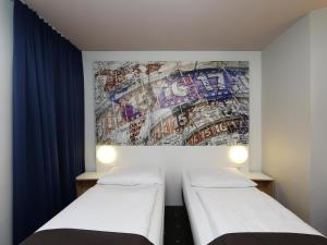 柏林B&B HOTEL Berlin-Alexanderplatz的墙上壁画的房间里设有两张床