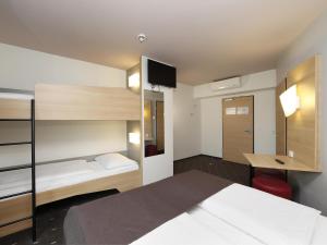 柏林B&B HOTEL Berlin-Alexanderplatz的一间卧室配有一张床、一张桌子和一张双层床。