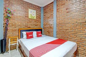 日惹OYO 92606 Djoglo Boto Homestay Syariah的一间卧室设有砖墙和一张带红色枕头的床