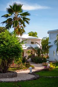 吉汶瓦Diamonds Mapenzi Beach的棕榈树和花园的白色房子