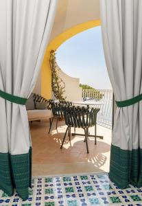 波西塔诺麦润科图酒店的阳台配有窗帘和桌椅