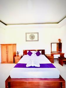 金塔马尼巴图尔火山旅馆的一间卧室配有一张带紫色床单的大床