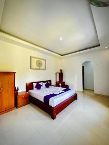 金塔马尼巴图尔火山旅馆的一间卧室配有一张带紫色枕头的大床