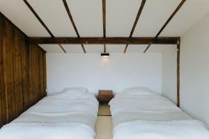 富士吉田市HOSTEL SARUYA 的白色床单的房间里一排床