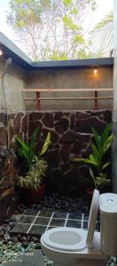 龙目岛库塔Mengalung Bungalow的浴室设有石墙、卫生间和植物
