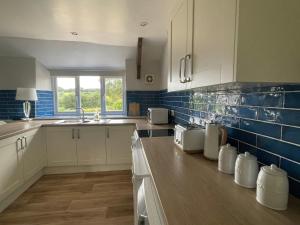 SimonsbathWinstitchen Cottage的厨房配有白色橱柜和蓝色瓷砖墙壁