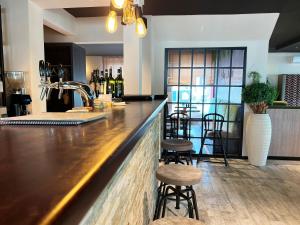 新基兴Hotel Da Toni的酒吧设有2张凳子和1个带葡萄酒瓶的吧台