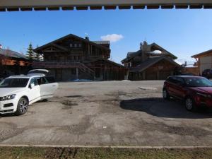 拉普德兹Appartement Huez, 1 pièce, 4 personnes - FR-1-405-48的两辆汽车停在房子前面的停车场