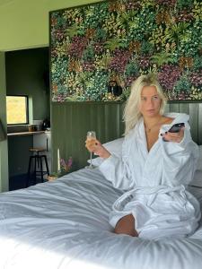 班特里Wild Hideaways Luxury Lodges and Eco Spa的坐在床上的女人,喝一杯酒
