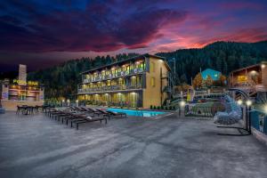 Solo Grand Boshuri Hotel Wellness Resort的一座带长凳和夜间游泳池的大型建筑