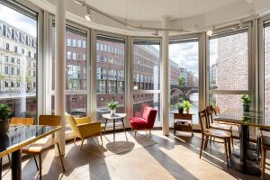 汉堡Ruby Lotti Hotel Hamburg的大型客房设有桌椅和大窗户。