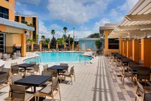 奥兰多奥兰多环球影城度假村对面凯悦嘉轩酒店的酒店庭院设有桌椅和游泳池