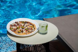 蒙特雷Camino Real Fashion Drive Monterrey的游泳池畔的餐桌上摆着比萨饼和饮料