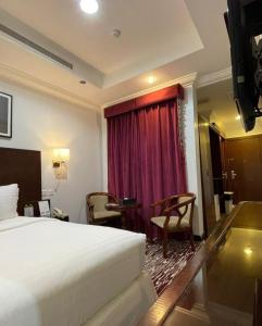 利雅德Carawan Al Khaleej Hotel Olaya的酒店客房,配有床和红色窗帘