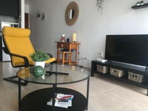 科斯塔特吉塞One bedroom bungalow Playa Bastian Costa Teguise的客厅配有玻璃桌、黄椅和电视