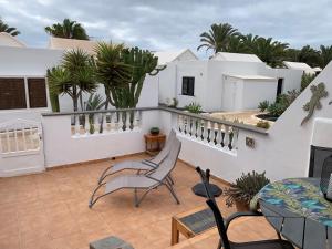 科斯塔特吉塞One bedroom bungalow Playa Bastian Costa Teguise的阳台,阳台上摆放着椅子和植物