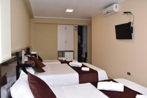齐克拉约Aura Hotel的酒店客房设有四张床和平面电视。